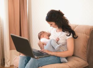 Beautiful young mother using Fit2B while breastfeeding holding and nursing her newborn baby at home - fit2b.com